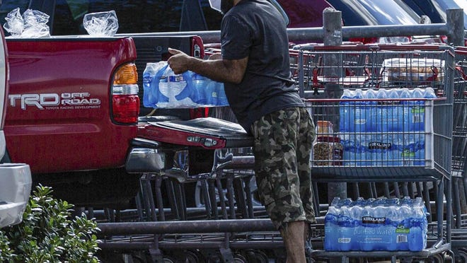 A man loads cases of water into the back of his pickup truck ahead of Tropical Storm Isaias, at Costco Thursday in Lantana.