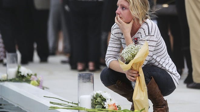 Julie Prudhomme kneels at Remembrance Plaza Monday, January 12, 2015, following a Celebration of Life service for Lynn University’s four students and two instructors who perished during the 2010 earthquake that devastated Haiti. Prudhomme, who survived the earthquake, said she remembers the earth crumbling beneath the group that tragic day. (Damon Higgins / The Palm Beach Post)