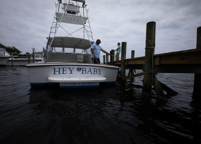 Kevin Moak, left, captain of the 30-foot 1974 G&S boat "Hey Baby," and Eddie Morgan, owner of Harbor Docks, a family-owned marina and seafood restaurant in Destin, Fla., maneuver the vessel April 1, 2024. (Tyler Orsburn/News Herald)