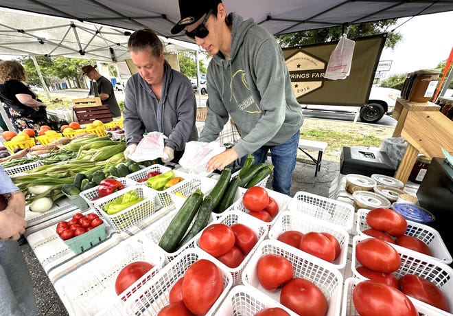 This vendor from Elba, Alabama bag up fresh vegetables for customers at the Destin Community Farmers Market on Sunday.