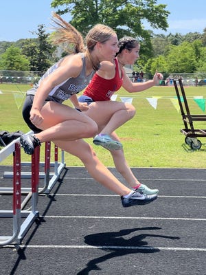 Destin's Evie Gherdovich clears a hurdle in the Okaloosa County Championships. She took first place in the 400-meter hurdles, a first for the Destin Sharks. Also pictured is Isabela Holbrook of Fort Walton Beach.