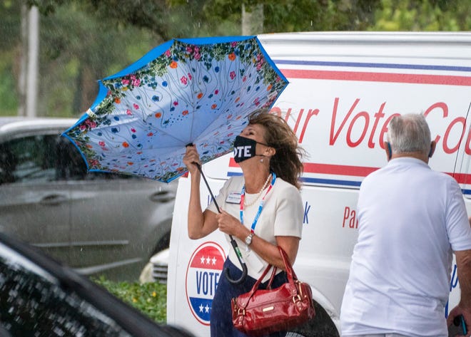 Palm Beach County Supervisor of Elections Wendy Satory Link holds onto her umbrella during a big gust of wind on the first day of early voting at the Palm Gardens Branch Library in Palm Beach Gardens , Florida on October 19, 2020. (GREG LOVETT / THE PALM BEACH POST)