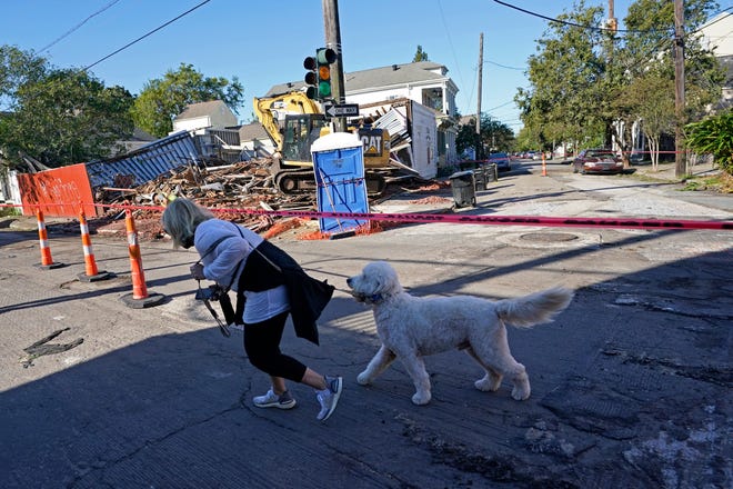 A person and dog walk past an unoccupied structure that collapsed the previous day as Hurricane Zeta swept through New Orleans, Thursday, Oct. 29, 2020. The storm left much of the city and metro area without power. (AP Photo/Gerald Herbert)